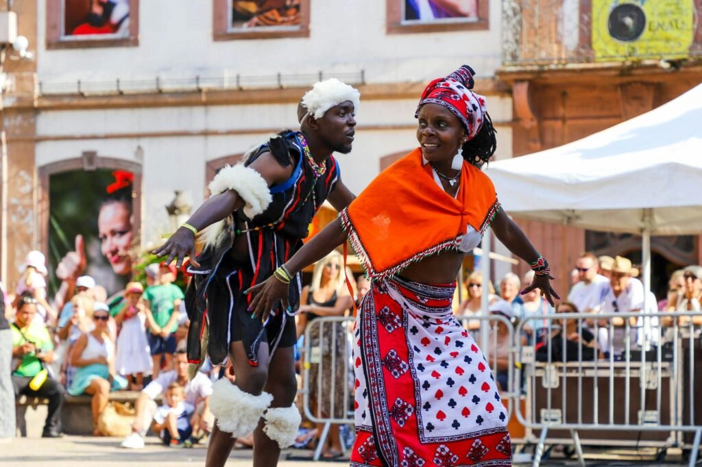 Joyful African dancers in traditional attire performing at an outdoor festival.