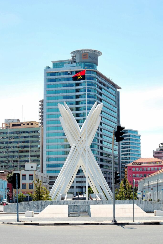 Urban scene featuring a modern skyscraper and unique monument in Luanda, Angola.