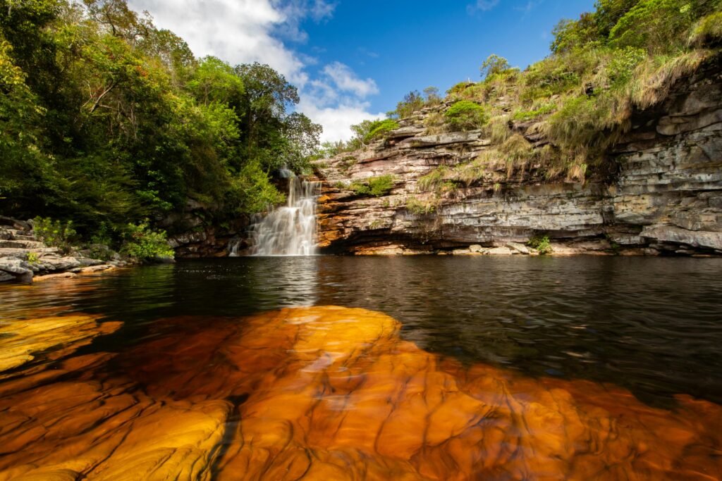 Tranquil tropical waterfall flowing into a serene pool surrounded by lush greenery.