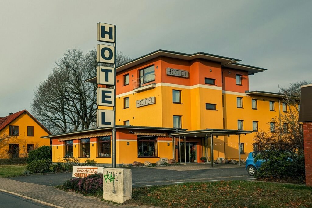 Vibrant yellow hotel exterior with signage under cloudy autumn sky.